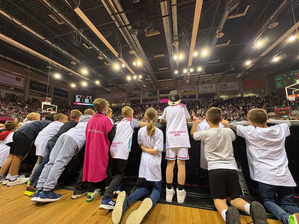 Kinder der F-Jugend verfolgen das Spiel der Telekom Baskets Bonn von der Bande am Spielfeldrand