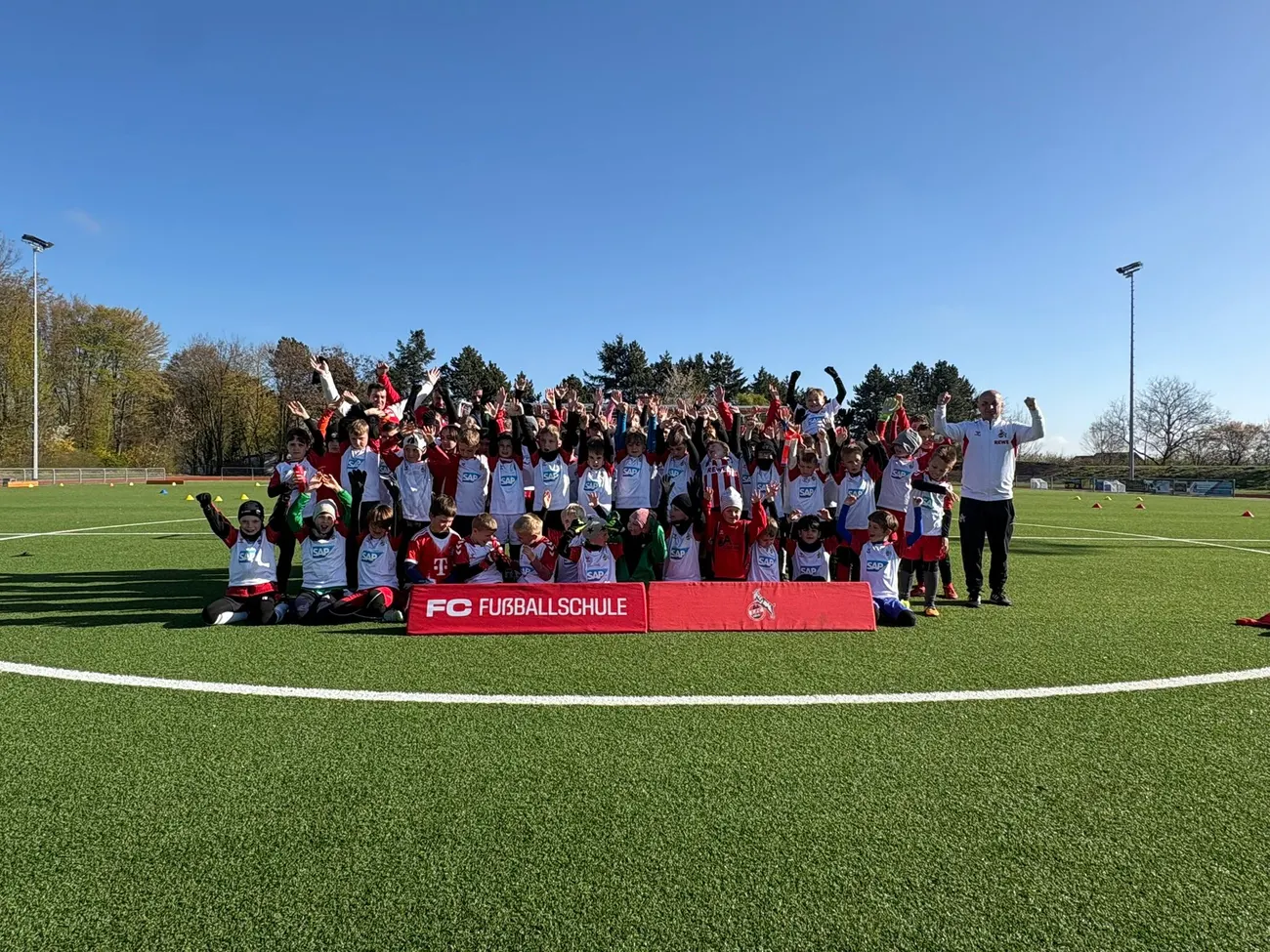 Alle Kinder des FC Fußballcamps jubeln beim Gruppenfoto auf dem Sportplatz des VfR Flamersheim