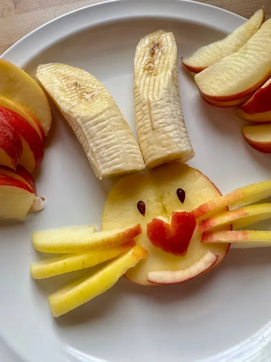 Teller mit Apfelspalten und Bananen, als Hasengesicht angerichtet, für die Obstpause im Camp