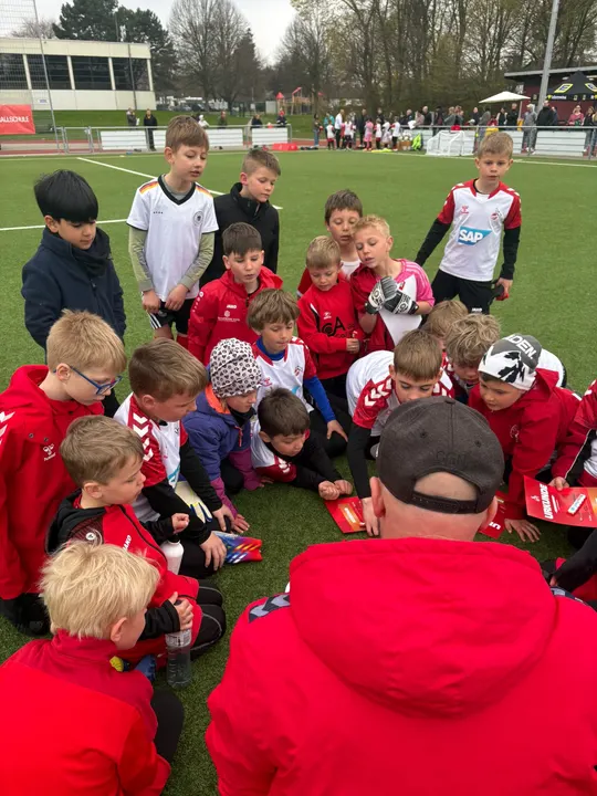 Trainer verteilt im Sitzkreis die Urkunden an die Kinder des Fußballcamps