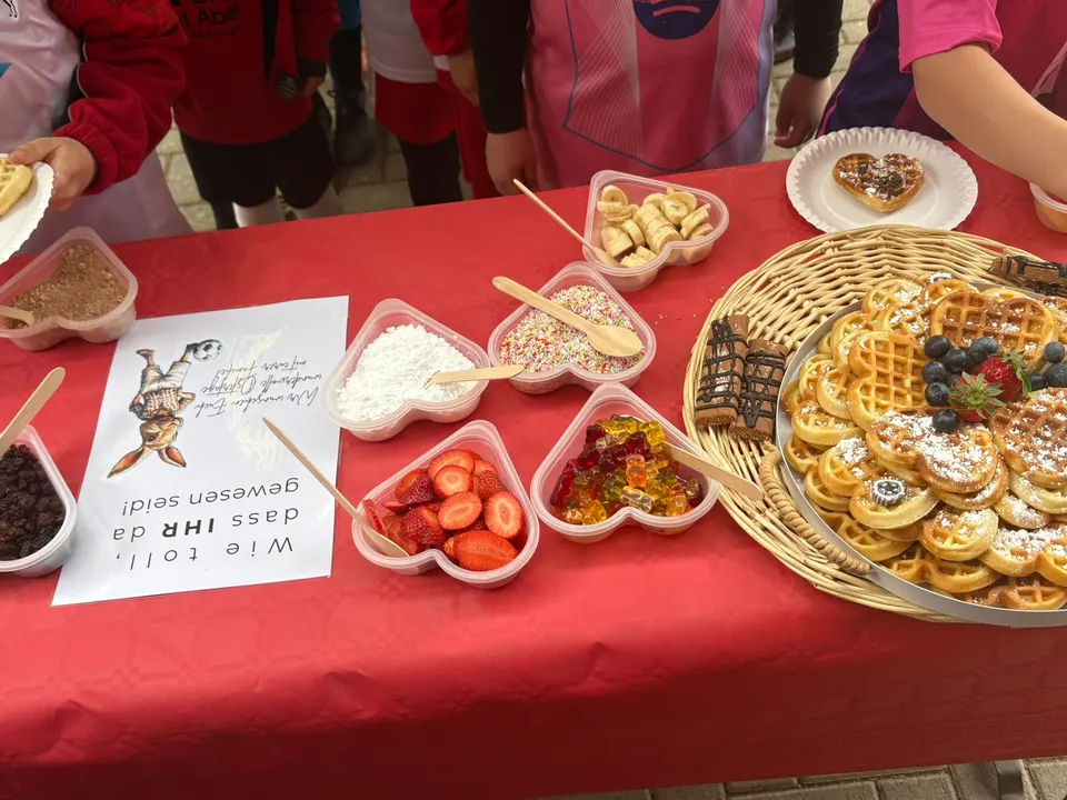 Tisch der Waffelbar mit Waffeln, Erdbeeren, Bananen und Streuseln in herzförmigen Schalen